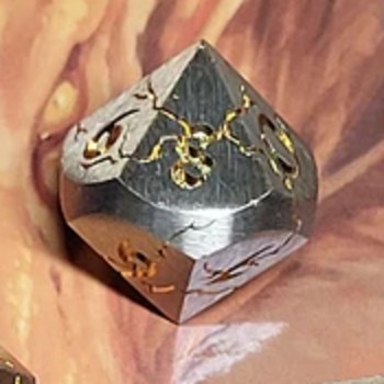 D10 — The Star die, full scale: a brushed silver metal ten-sided die with a gold star figure engraved on its faces, cropped from the set photo
