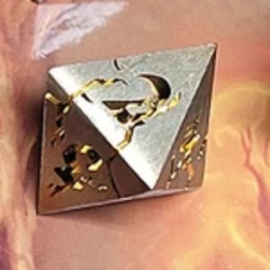 D4 — Crescent Moon die, full scale: a brushed silver metal four-sided tetrahedron with gold crescent-moon and star engraving, cropped from the set photo